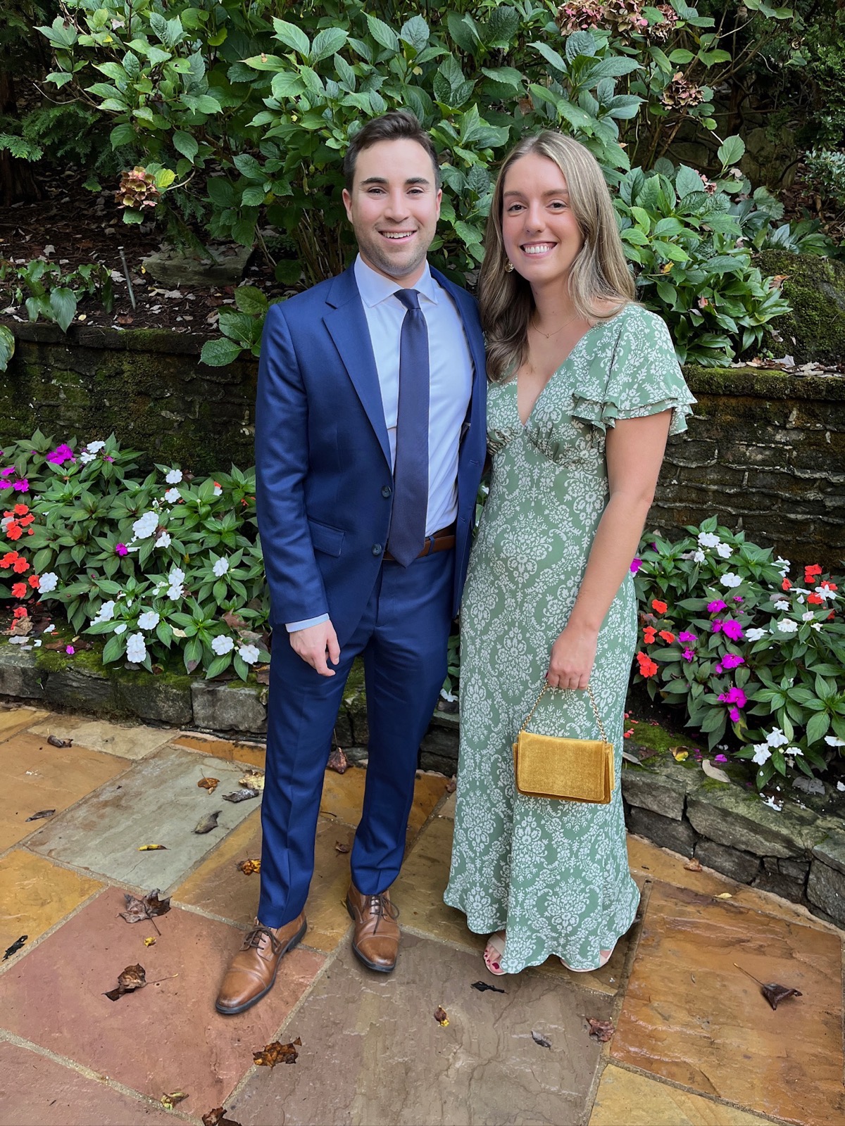 Caitlin and Paul dressed up in a garden, at a friend's wedding